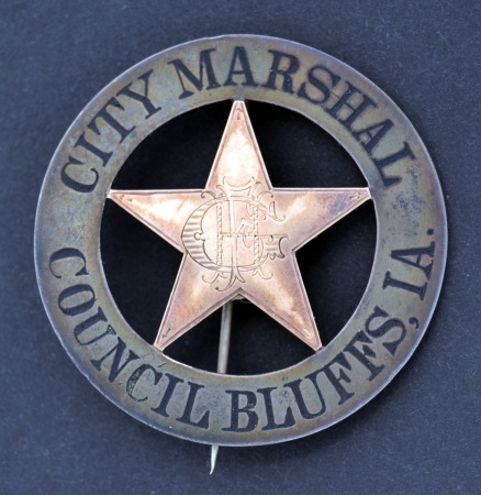 Council Bluffs, IA City Marshal badge, made of sterling silver with a 14k gold overlaid 5 point star with the letters F. H. G. monogramed in the center.  T pin and C.catch.  Jeweler made.