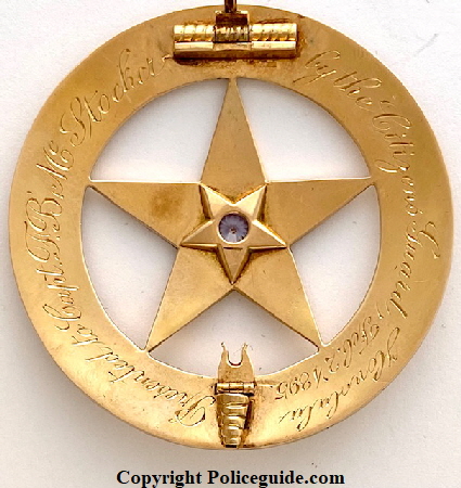 Back of badge showing T-pin, Megaphone Catch with safety bar and presentation:  Presented to Capt. F. B. McStocker by the Citizens Guard Honolulu Feb. 2, 1895. 