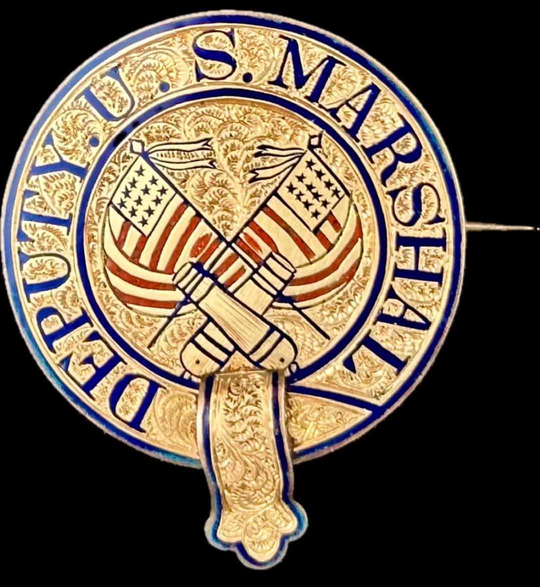 Post Civil War jeweler made Deputy U. S. Marshal badge made in the classic “police belt” design.  14k gold layered over a sterling silver base.  Red and blue hard fired enamel highlight the crossed U.S. flags and the crossed cannons.  