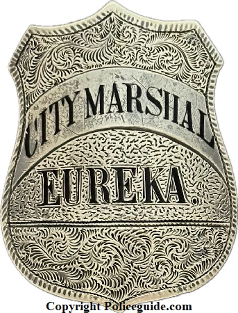 City Marshal Eureka shield, sterling silver, hand engraved, hard fired black enamel lettering.  The first City Marshal for Eureka was appointed in 1858.  On June 9, 1887 Ordinance 110 specifically designated the City Marshal as the ex-officio police chief.  In 1895 the title �City Marshal� was eliminated and the position of �Chief of Police� was created.