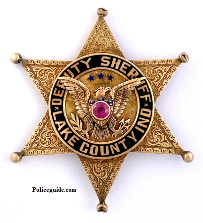 14k gold Lake County, IN Deputy Sheriff badge.  Hand engraved surmounted by an eagle with a red stone in the chest.  Lettering done in Black reverse enamel.