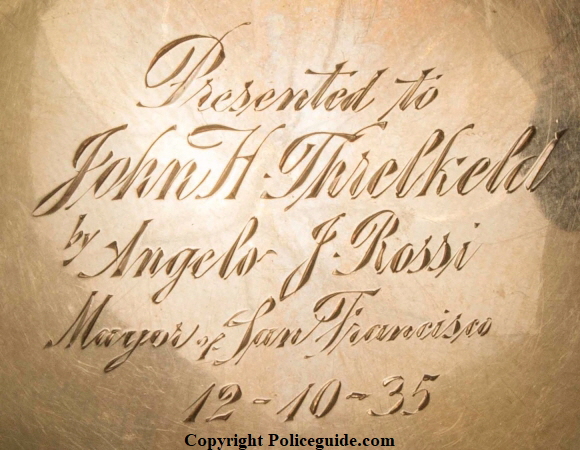 Reverse of badge showing presentation:  Presented to John H. Threlkeld by Angelo F. Rossi Mayor of San Francisco 12-10-35.  