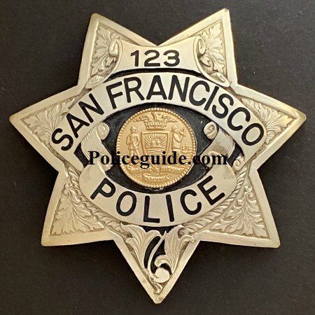 S.F.P.D. Prototype Badges.  Back in the 1970’s it was felt by the department that they should explore going to a more unique police badge.  Irvine & Jachens was tasked with coming up with new designs for consideration.  These three prototype’s were considered.  Badge number 88 was the badge number assigned to officer Russ Dickey.   Russ was issued the badge to wear on duty and seek opinions and feedback from fellow officers and the public.  Both badges 88 and 123 are sterling silver with hand engraved leafing highlighted by recessed black enamel.  Badge 0000 was a departure from the 7 point star worn for more than 100 years.  The badge featured reverse blue enameled panels and borders and a sterling silver city seal.  Tradition won out and it was decided no change would be made.  To this day badge 88 worn by Russ Dickey is the only department authorized prototype badge to be worn.